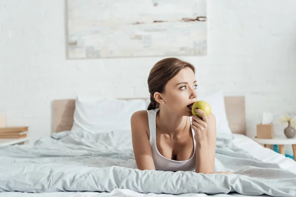 Pensosa Giovane Donna Mangiare Mela Verde Letto — Foto Stock