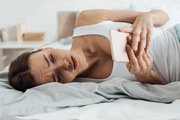 Menekankan Wanita Muda Berbaring Tempat Tidur Dan Menggunakan Smartphone — Stok Foto