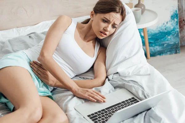 Chateado Jovem Deitado Cama Com Laptop Tocando Barriga — Fotografia de Stock