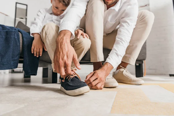 自宅で靴ひもを結ぶ息子を教える父の部分的な見解 — ストック写真