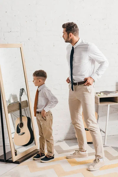 儿子和父亲在正式穿着站在镜子附近的全长视图 — 图库照片