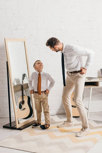 儿子和父亲在正式穿站在镜子附近 看着对方全长视图 — 图库照片