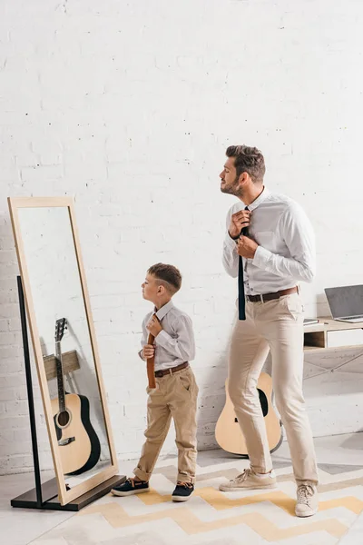 鏡の近くに立つフォーマルな服装で息子と父親の全長図 — ストック写真