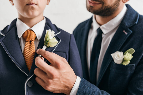 partial view of son and dad in jackets with boutonnieres