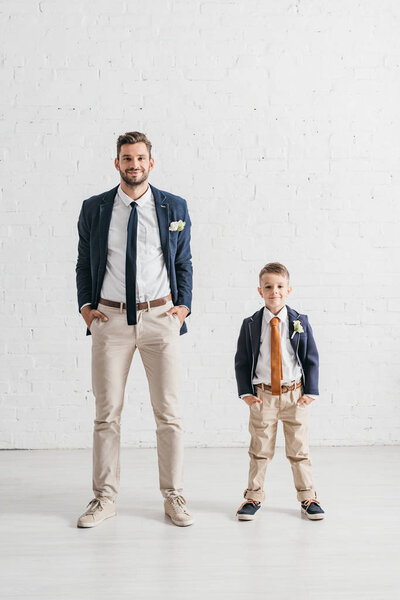 full length view of father and son in jackets with boutonnieres 
