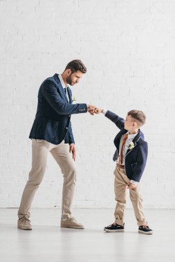 boutonnieres birbirlerine bakarak ceketli baba ve oğul tam uzunlukta görünümü