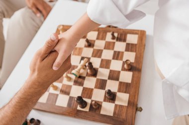 satranç tahtası üzerinde el sıkışma baba ve oğlu kısmi görünümü 