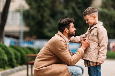 sonbahar gününde sokakta ceketli ceketli baba ve oğlu yan görünümü