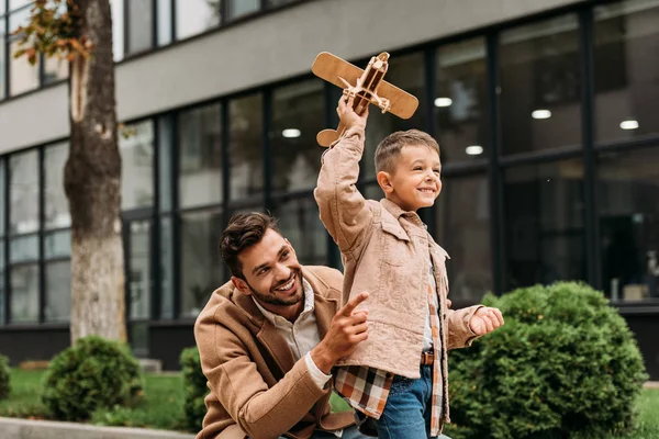 Pai Casaco Elegante Sorrindo Filho Segurando Avião Brinquedo Rua — Fotografia de Stock