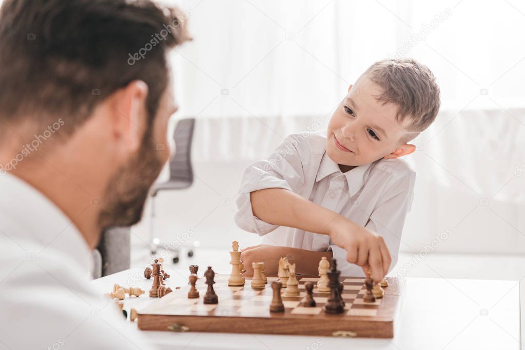 selective focus of dad and son playing chess together at home