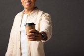 Ausgeschnittene Ansicht eines Mannes mit gemischter Rasse in beigem Hemd mit Kaffee auf schwarzem Hintergrund