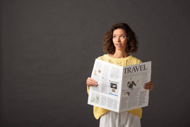 siyah arka plan üzerinde seyahat gazetesi tutan sarı örme kazak rüya gibi kıvırcık kadın