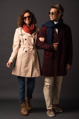 siyah arka plan üzerinde el ele tutuşan sonbahar kıyafeti gülümseyen şık ırklararası çift