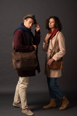 siyah arka plan üzerinde çanta ile sonbahar kıyafeti şık ırklararası çift