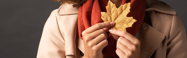 панорамный снимок женщины в плаще с золотым кленовым листом на черном фоне
