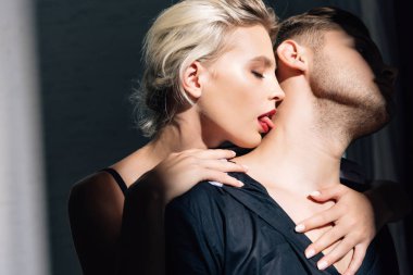 attractive woman with red lips kissing man in shirt 