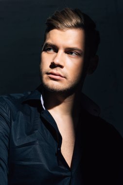 Siyah gömlekli yakışıklı daireye bakıyor. 