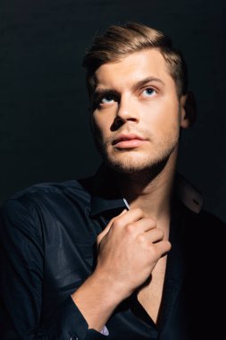 Siyah gömlekli yakışıklı daireye bakıyor. 