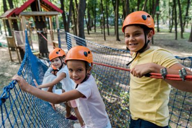selective focus of happy kids standing on high rope trail  clipart