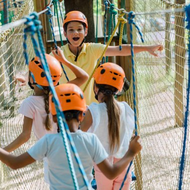 selective focus of happy boy near multicultural friends in adventure park  clipart