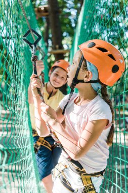 selective focus of adorable kids in helmets with height equipment in adventure park  clipart