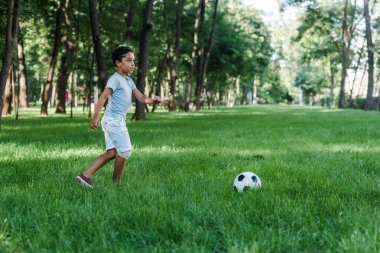 tapılası Afrikalı Amerikalı çocuk yeşil çimlerde futbol oynuyor. 