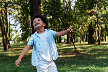 happy african american boy looking up in park  clipart