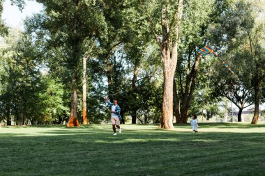 mutlu afrikalı amerikalı oğlu ve baba parkta çim üzerinde çalışan 
