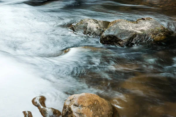 selective focus of wet stones near flowing brook 