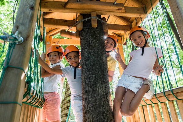 cheerful multicultural kids in helmets smiling while looking at camera