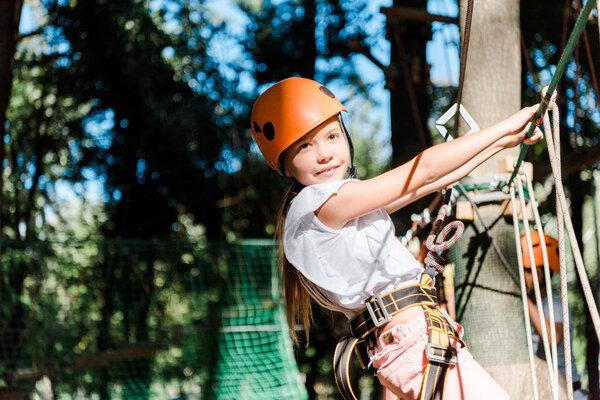cheerful kid in helmet with height equipment in adventure park 