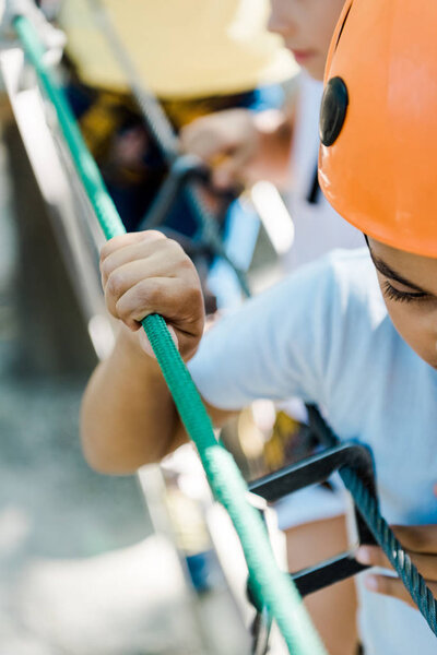 cropped view of african american boy in helmet near friend in adventure park 