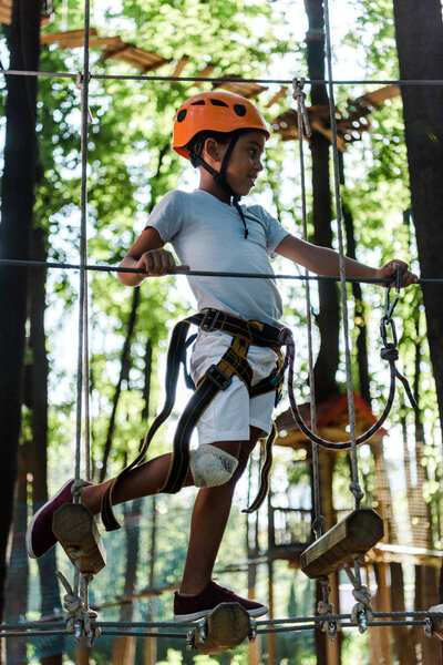 happy african american child in orange helmet in adventure park 