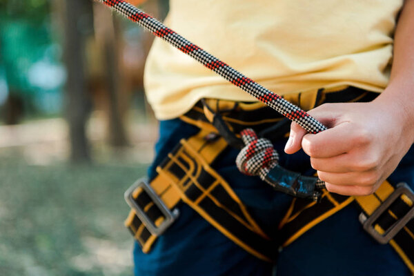 cropped view of boy holding rope while standing outside 