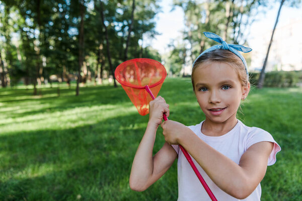 positive child holding butterfly net in green park 