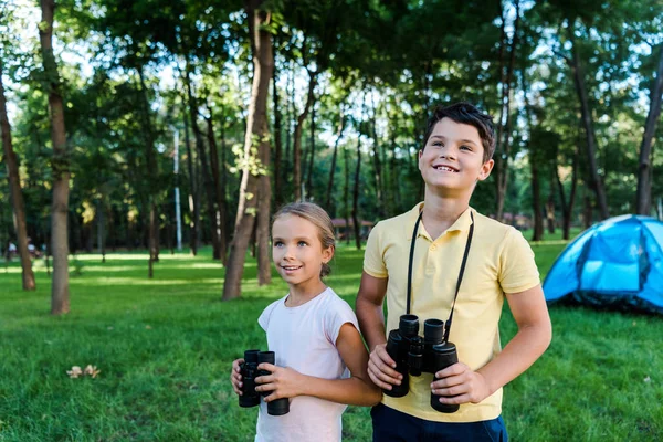 Niños Felices Sonriendo Mientras Sostienen Prismáticos Cerca Del Campamento — Foto de Stock