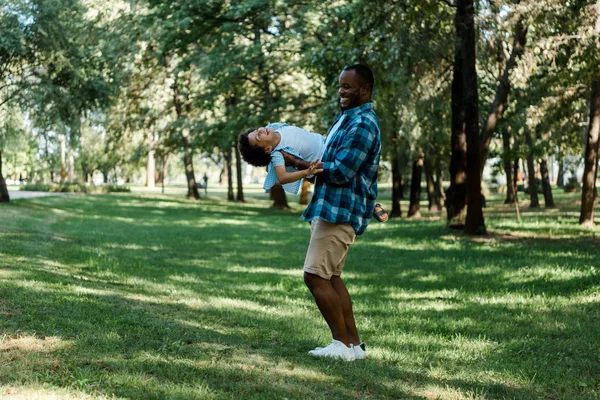 公園でかわいい息子を腕に抱いて幸せなアフリカ系アメリカ人の父親 — ストック写真
