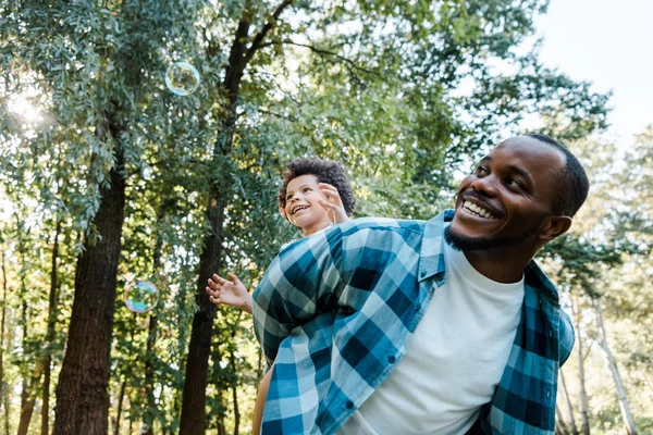 Niedrigwinkel Ansicht Der Glücklichen Afrikanisch Amerikanischen Huckepack Niedlichen Lockigen Sohn — Stockfoto