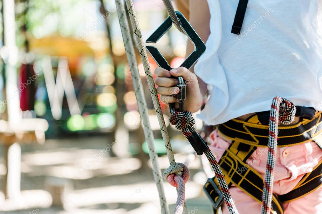 cropped view of kid with safety equipment in adventure park 