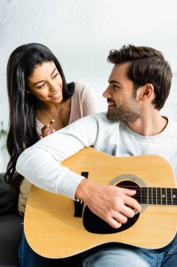 akustik gitar ile adam bakarak gülümseyen afrikalı amerikalı kadın