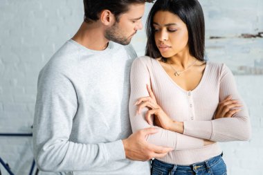 yakışıklı adam çapraz kolları ile üzgün afro-amerikan kadın sarılma 