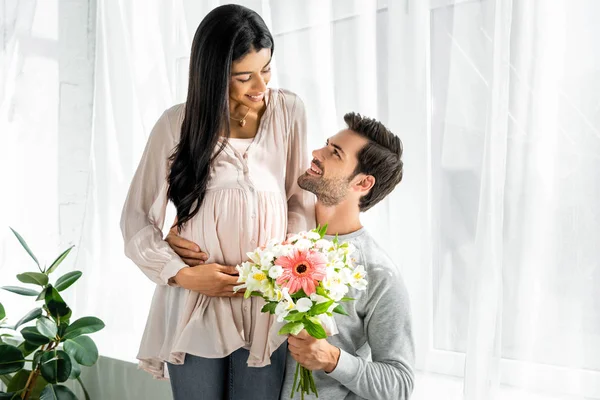 Schöner Mann Umarmt Bauch Seiner Schwangeren Afroamerikanerin Und Hält Blumenstrauß — Stockfoto