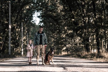 Alman çoban köpeğinin yanında çocukla el ele tutuşan adam, kıyamet sonrası konsepti.