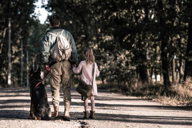 back view of man holding hands with kid near german shepherd dog, post apocalyptic concept clipart