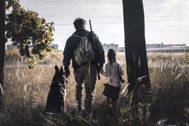 back view man standing in field with kid and german shepherd dog, post apocalyptic concept clipart