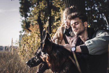 Çocuğun yanında Alman çoban köpeğine dokunan bir adamın seçici odağı, kıyamet sonrası konsepti.