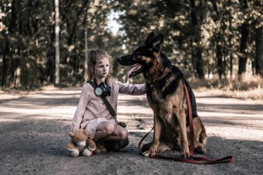 upset kid with teddy bear touching german shepherd dog on road, post apocalyptic concept clipart