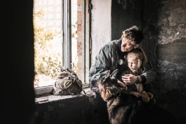 Terk edilmiş binada Alman çoban köpeğine sarılan bir adam, kıyamet sonrası konsepti.