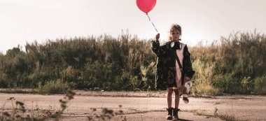 panoramic shot of cute kid with gas mask holding balloon, post apocalyptic concept clipart
