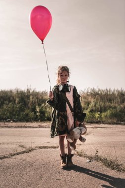 Gaz maskeli tatlı çocuk elinde kırmızı balon, kıyamet sonrası konsepti